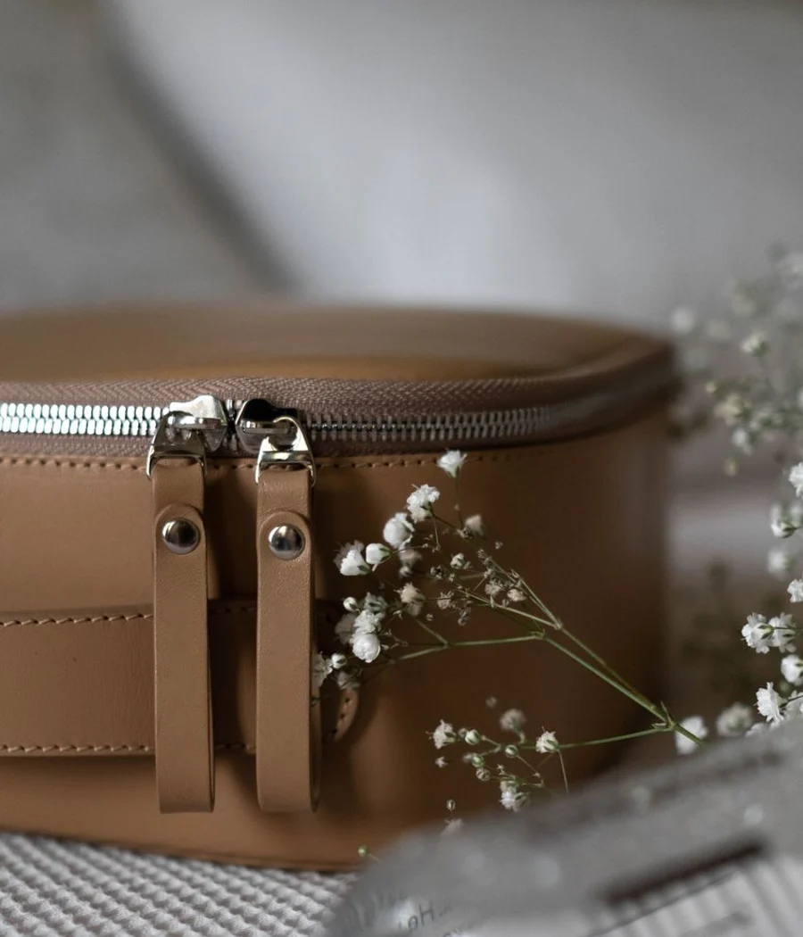 Detail of a tan zippered utility pouch on textured fabric