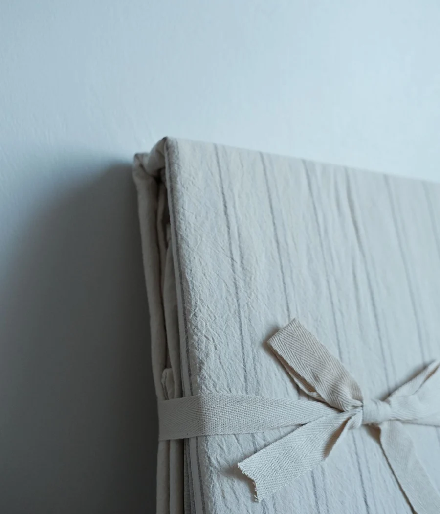A folded ivory woven blanket tied with a fabric ribbon