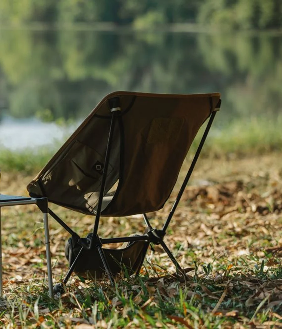 A folding fabric camp chair beside a quiet lake