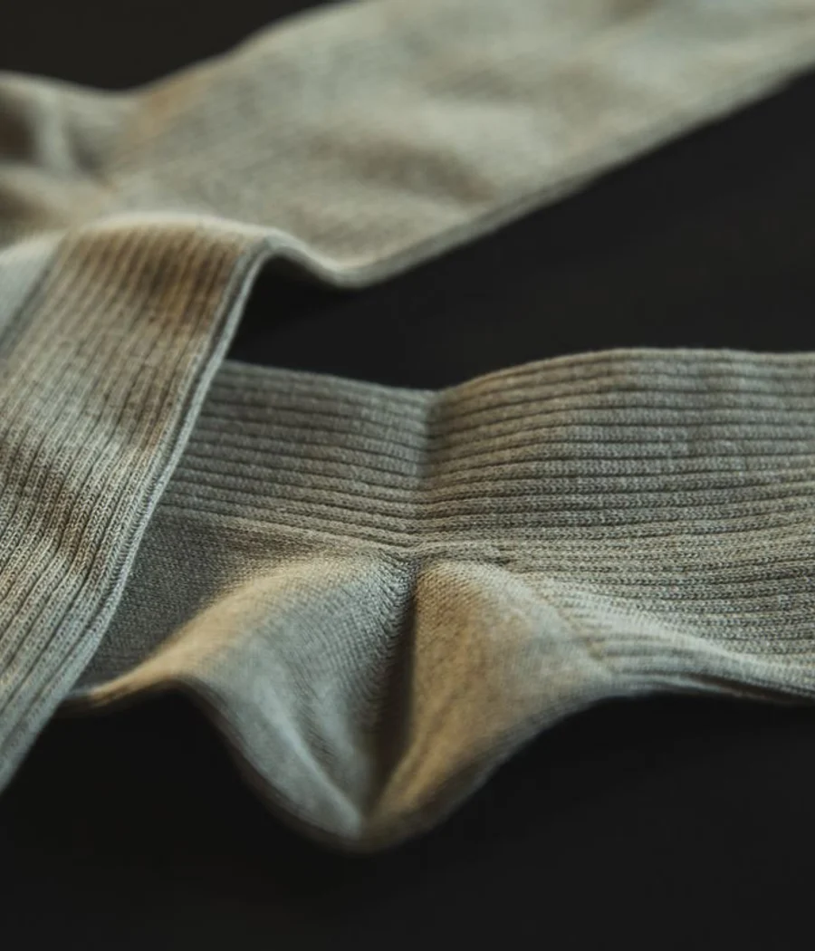 A pair of gray ribbed socks on a dark background